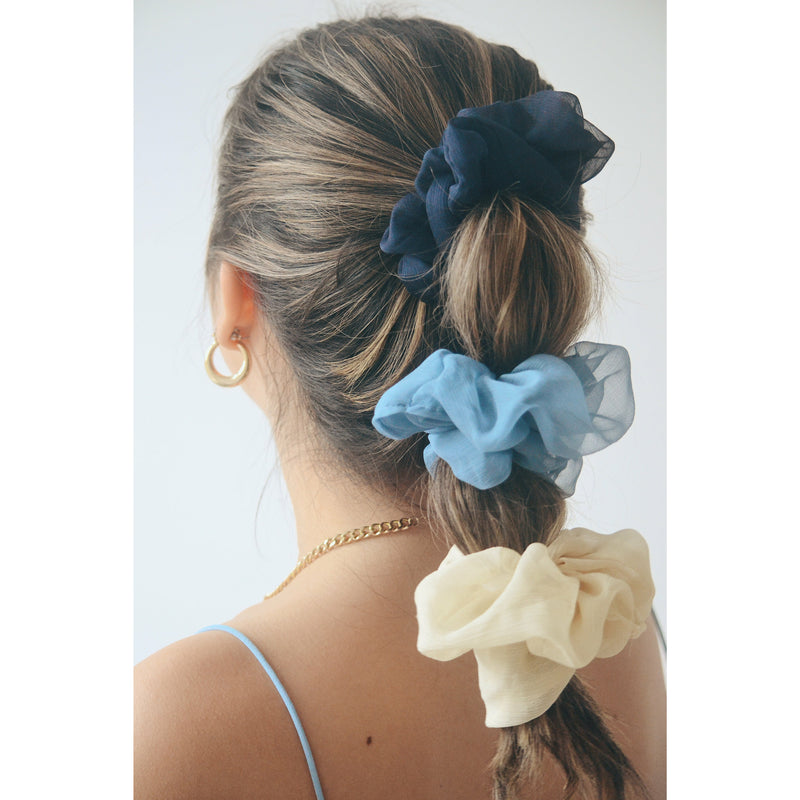 group of three chiffon silk scrunchies in blue, dark blue, and off white all on one pony tail